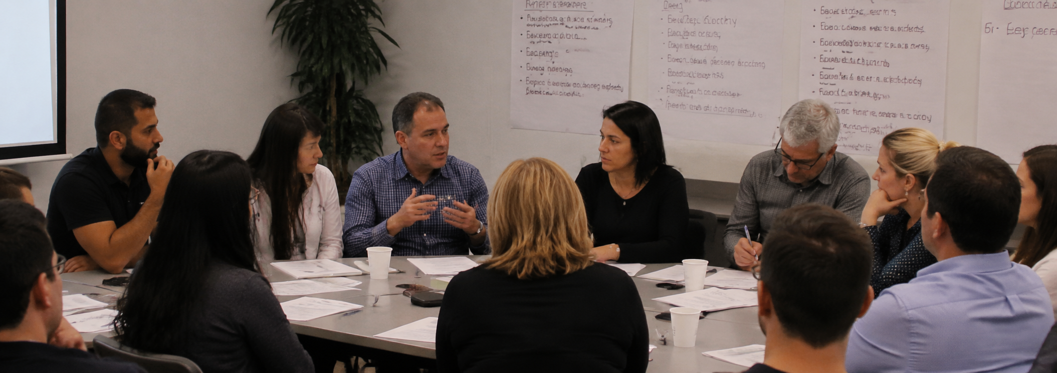 Business owners and professionals collaborate around a table during a group learning and strategy session.