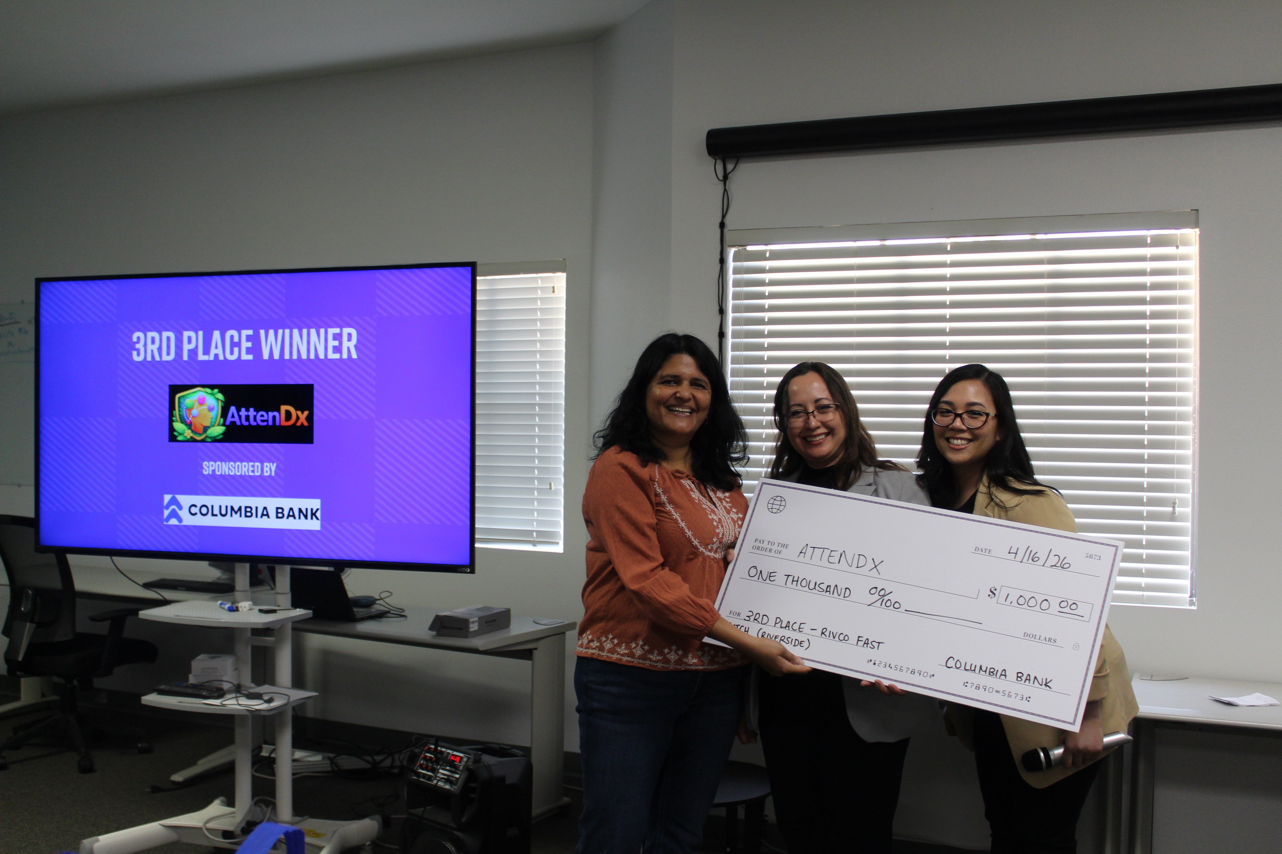 3rd Place Winner, AttenDx, represented by Anubhuti Goel, together with Maricela Covarrubias-Argueta, Incubator Manager of Riverside ExCITE, and Aileen Luib, Assistant Director of Special Programs and Outreach at UC Riverside, holding a check of $1,000 issued by Columbia Bank.