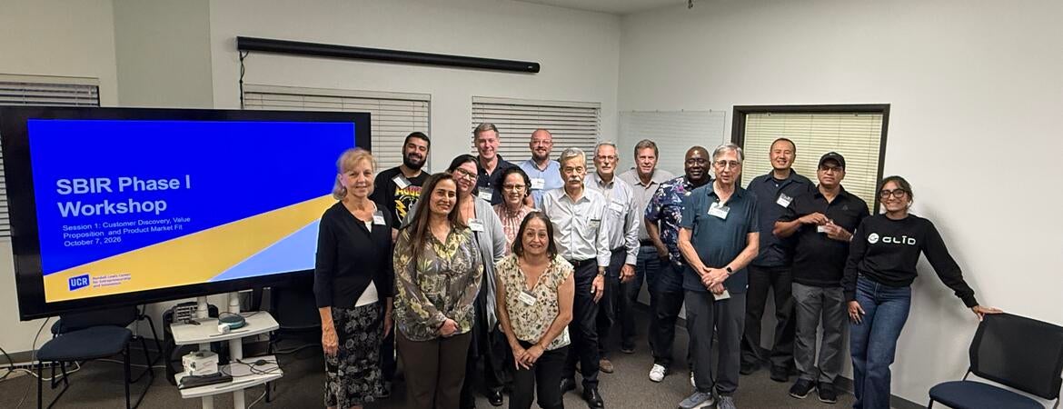 Group photo of UC Riverside's inaugural SBIR Phase I Workshop participants, instructors, and mentors standing together beside a presentation screen during the October 7, 2026 session.