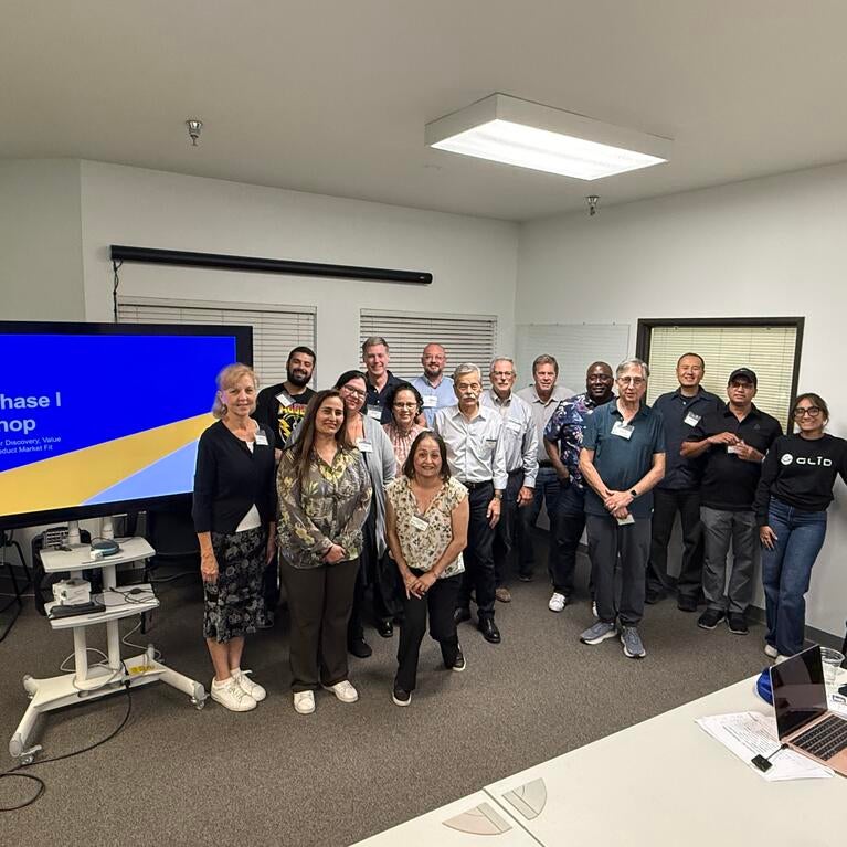 Group photo of UC Riverside's inaugural SBIR Phase I Workshop participants, instructors, and mentors standing together beside a presentation screen during the October 7, 2026 session.