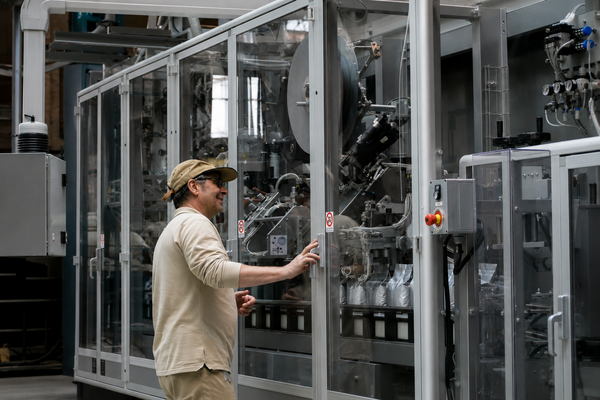 Man in front of a large invention behind a glass door