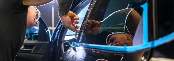 A man applying tint to a vehicle window