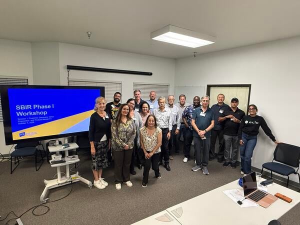 Group photo of UC Riverside's inaugural SBIR Phase I Workshop participants, instructors, and mentors standing together beside a presentation screen during the October 7, 2026 session.